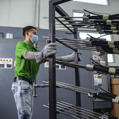 A worker wearing PPE and moving a metal rack